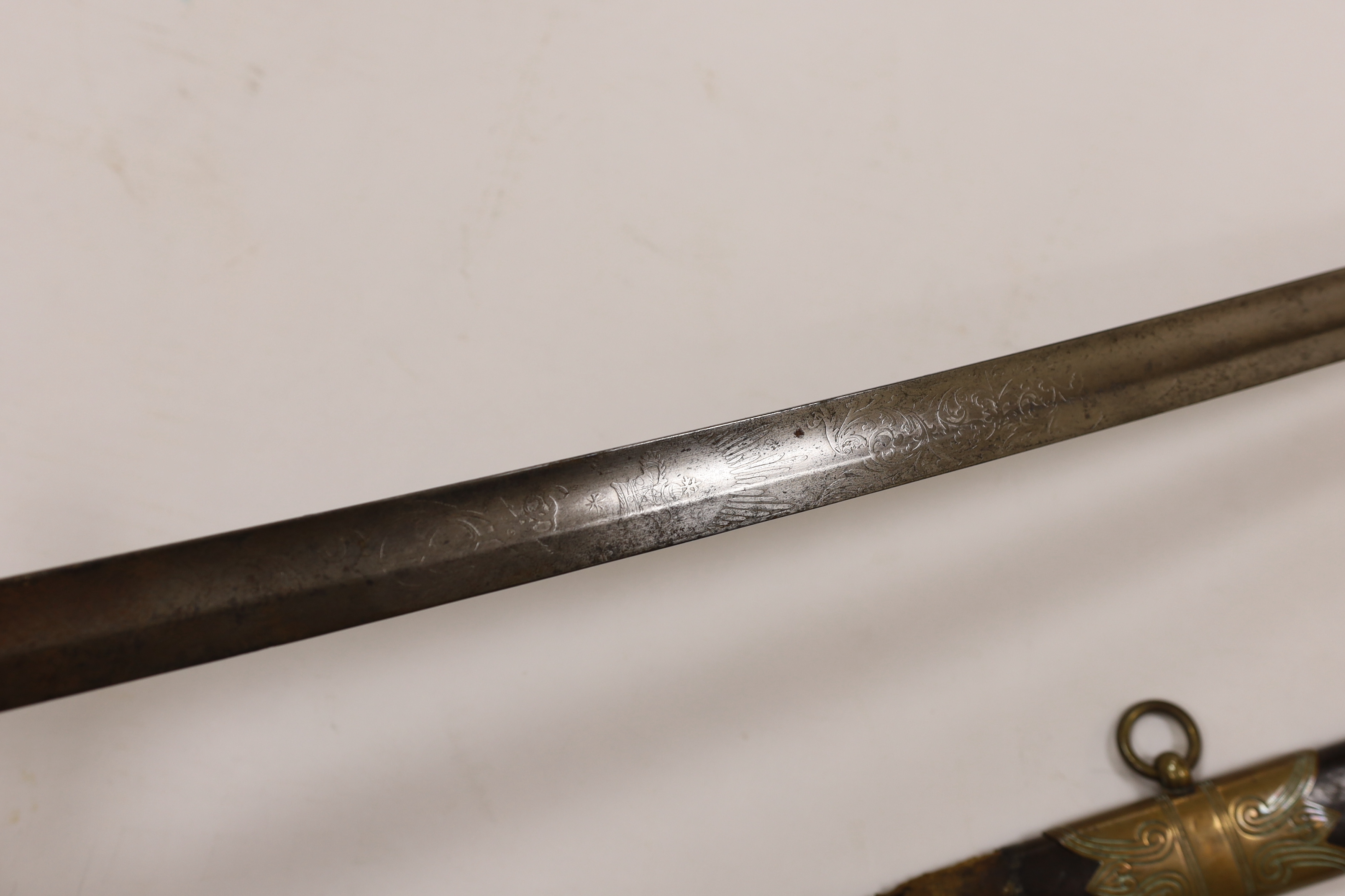 A late Victorian naval officer’s sword with regulation brass hilt, lion head pommel and blade etched with crown, VR and fouled anchor in its leather scabbard, top mount missing, blade 77cm